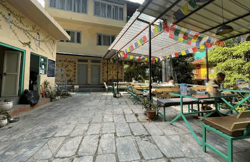 The stone courtyard with picnic benches under strings of prayer flags