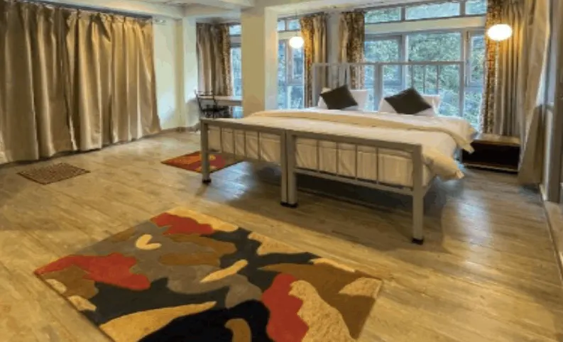 A private room with a double bed, rug and windows onto the trees