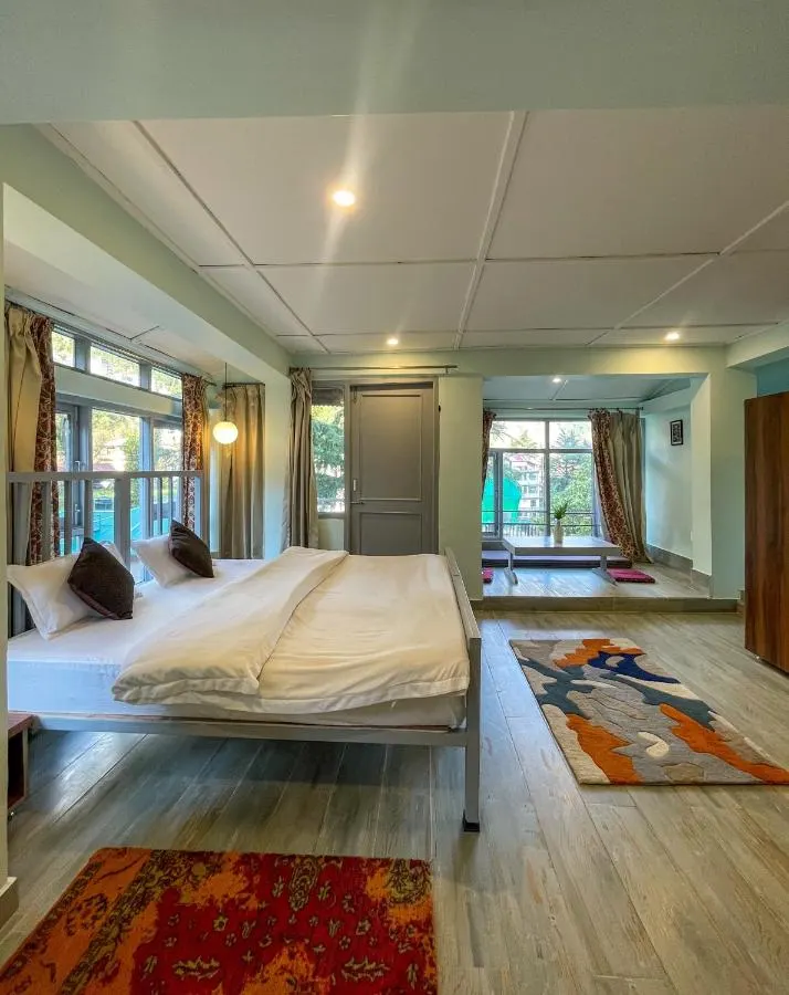 A spacious room with a double bed and a seating area by the windows