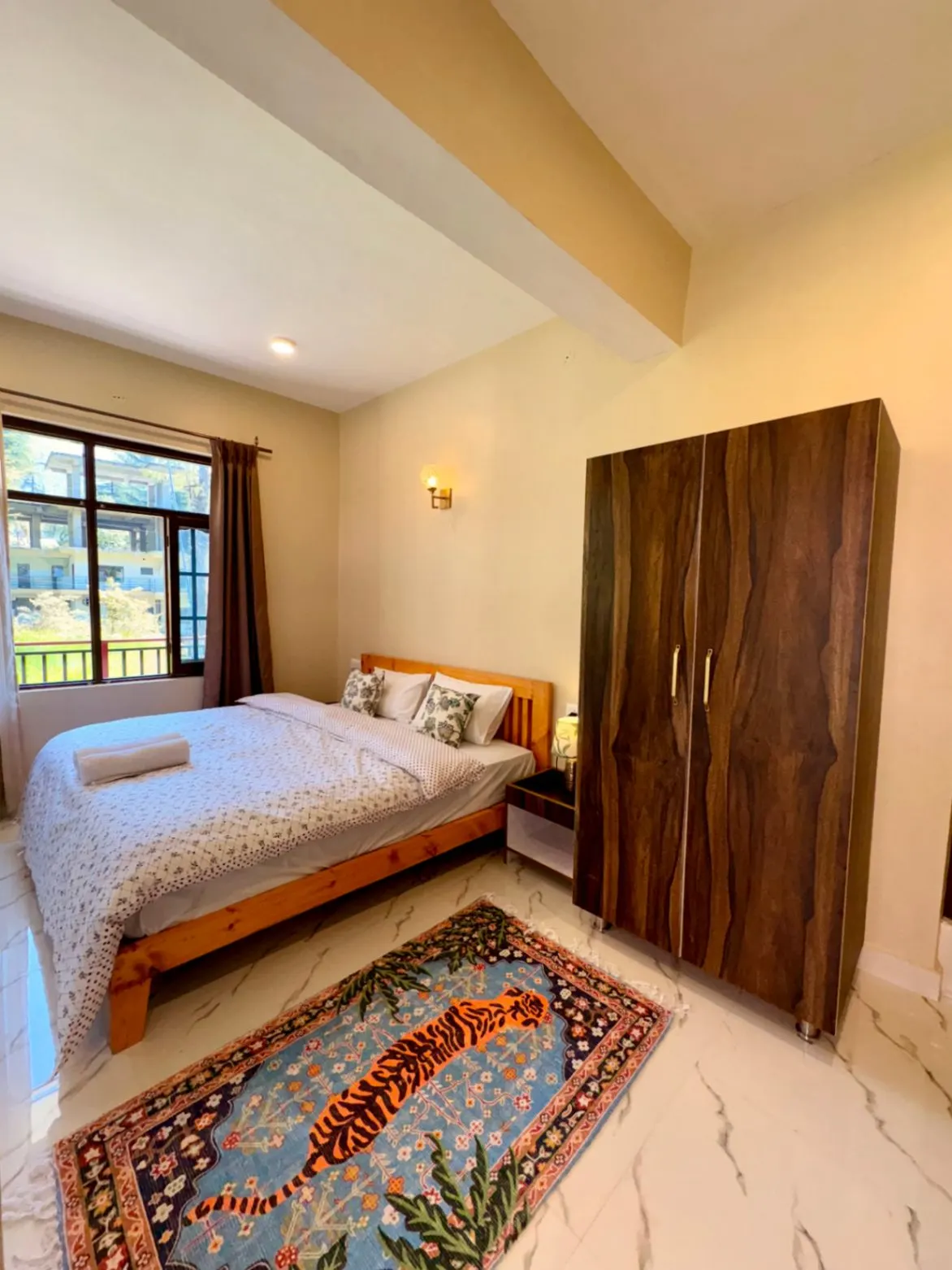 An Evolve Home king room with a wooden wardrobe and a garden-facing window