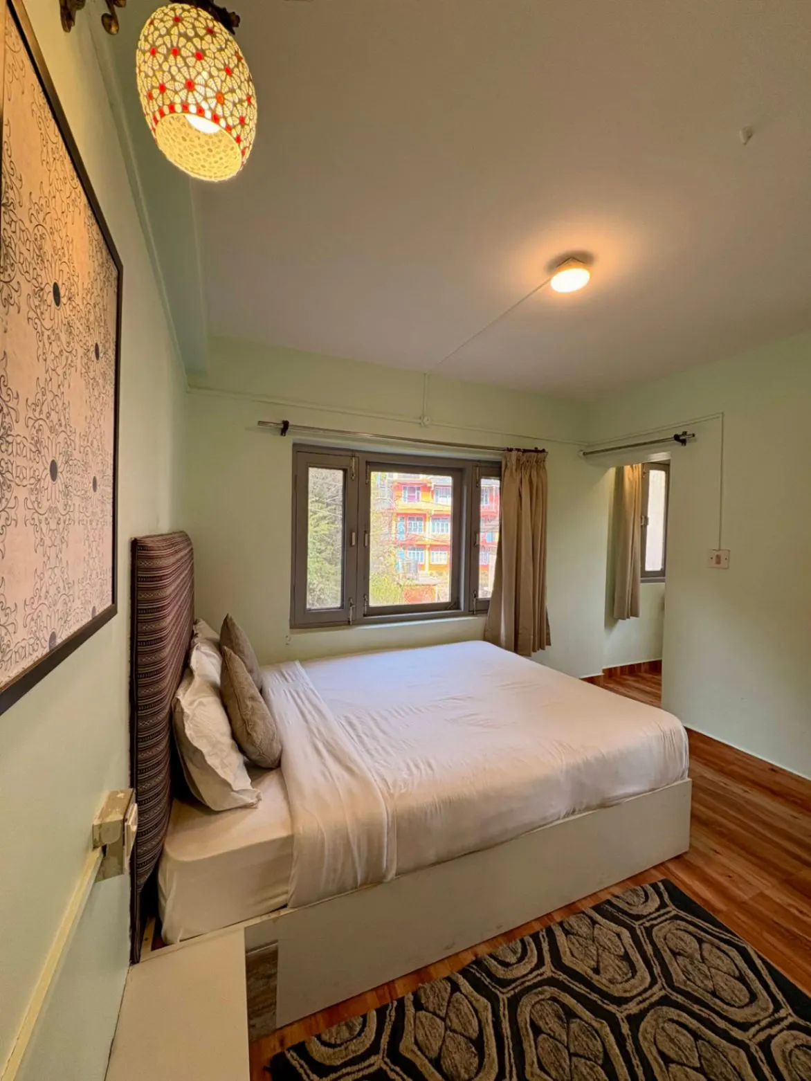 A queen room with a soft-lit corner and a window